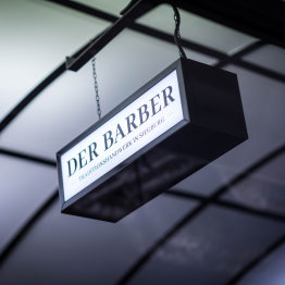 Das Bild zeigt ein Eingangsschild mit der Aufschrift des Barbershops