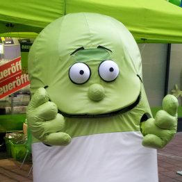 Das Bild zeigt ein grünes Maskotchen der easyApotheke Siegburg City